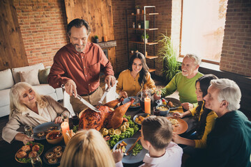Portrait of nice attractive cheerful family brother sister parents grandparents multi generation enjoying festal meal occasion cutting turkey at modern loft brick industrial interior indoors