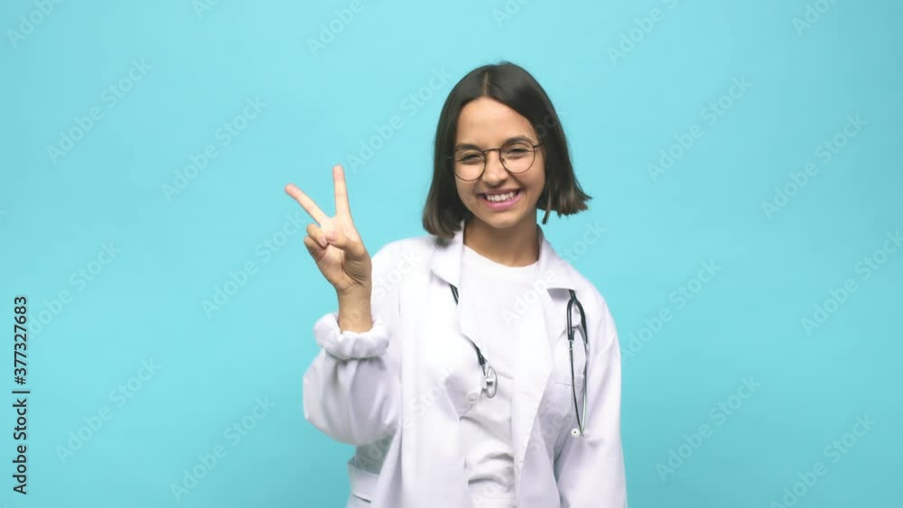 Young doctor indian woman joyful and carefree showing a peace symbol with fingers Young doctor indian woman joyful and carefree showing a peace symbol with fingers