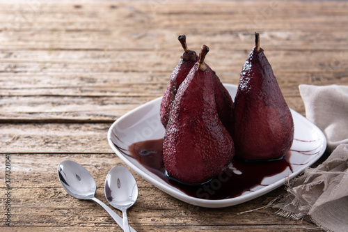 Poached pears in red wine on wooden table. Copy space 