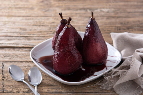 Poached pears in red wine on wooden table. 