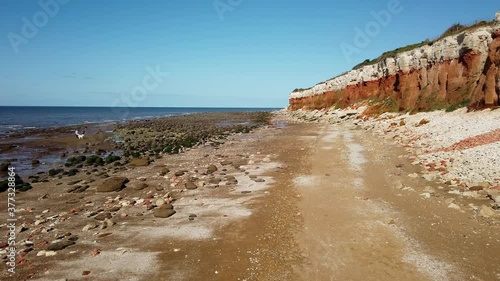 Pan from the sea to the red and white striped chalk limestone and sandstone cliffs at Hunstanton Norfolk England UK.