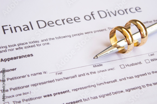 Two broken golden wedding rings divorce decree document. Divorce and separation concept photo