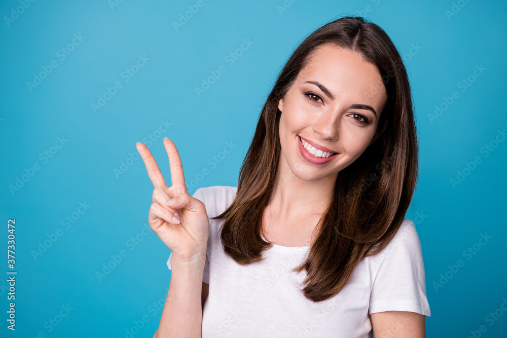 Portrait of attractive charming girl make v-sign enjoy weekend holiday wear casual style clothes isolated over blue color background Portrait of attractive charming girl make v-sign enjoy weekend holiday wear casual style clothes isolated over blue color background