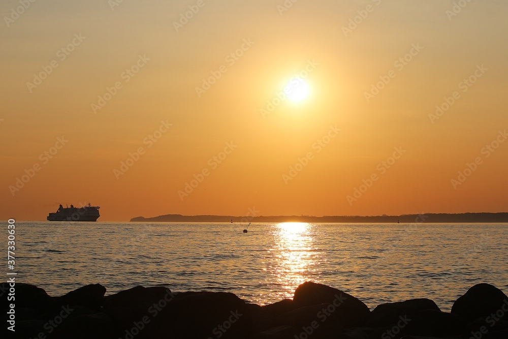 a large transport ship enters the port early in the morning at sunrise