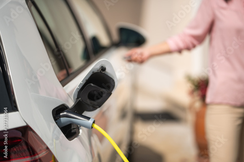 Close up of a electric car charger with female silhouette in the background