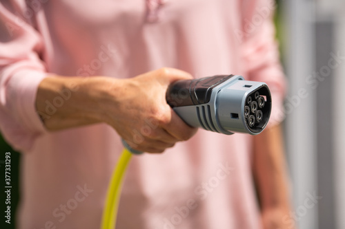 Close up of a hand holding an electric car charger