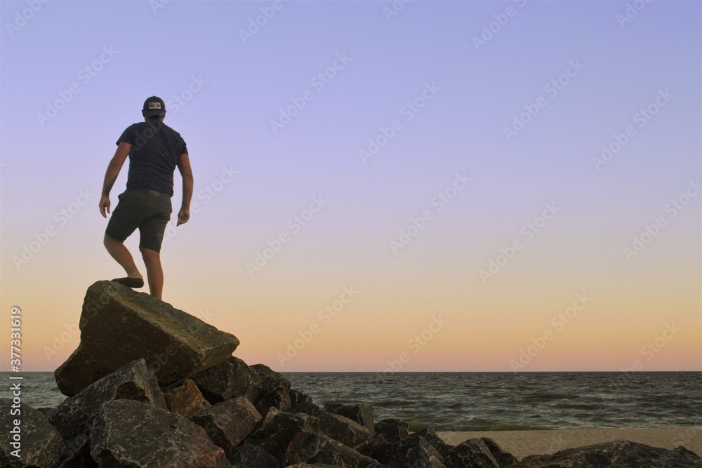 The guy on the stones looks to the horizon