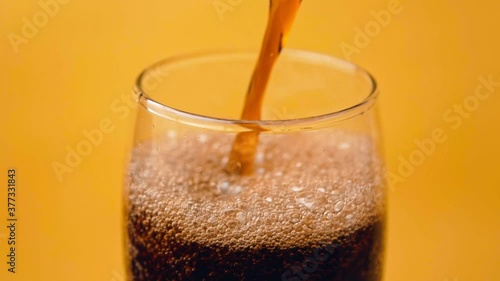 Wallpaper Mural Pouring cola into glass on yellow background in slow motion Torontodigital.ca