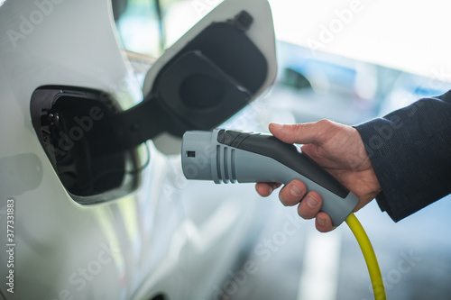Close up of a man's hand holding a electric car charger