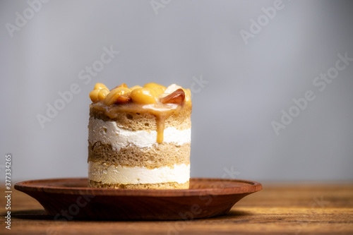 Obraz na plátně Macadamia nut coffe sponge cake with butterscotch sauce topping on brown wooden plate