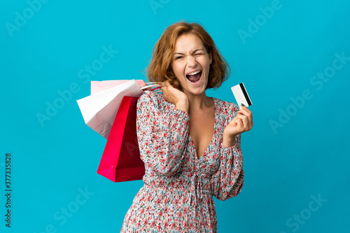 Young Georgian woman with shopping bag isolated on blue background holding shopping bags and a credit card