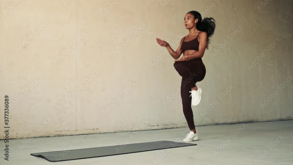 Young african sports woman making fat burning exercises isolated over white wall background Young african sports woman making fat burning exercises isolated over white wall background