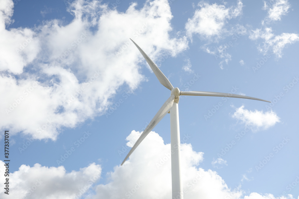 Wind turbine in a sunny day with blue sky and clouds. Wind farm eco field. Green ecological power energy generation. Wind turbine in a sunny day with blue sky and clouds. Wind farm eco field. Green ecological power energy generation.