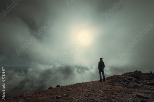Man silhouette standing in front of sun and fog on the mountain © Mihai