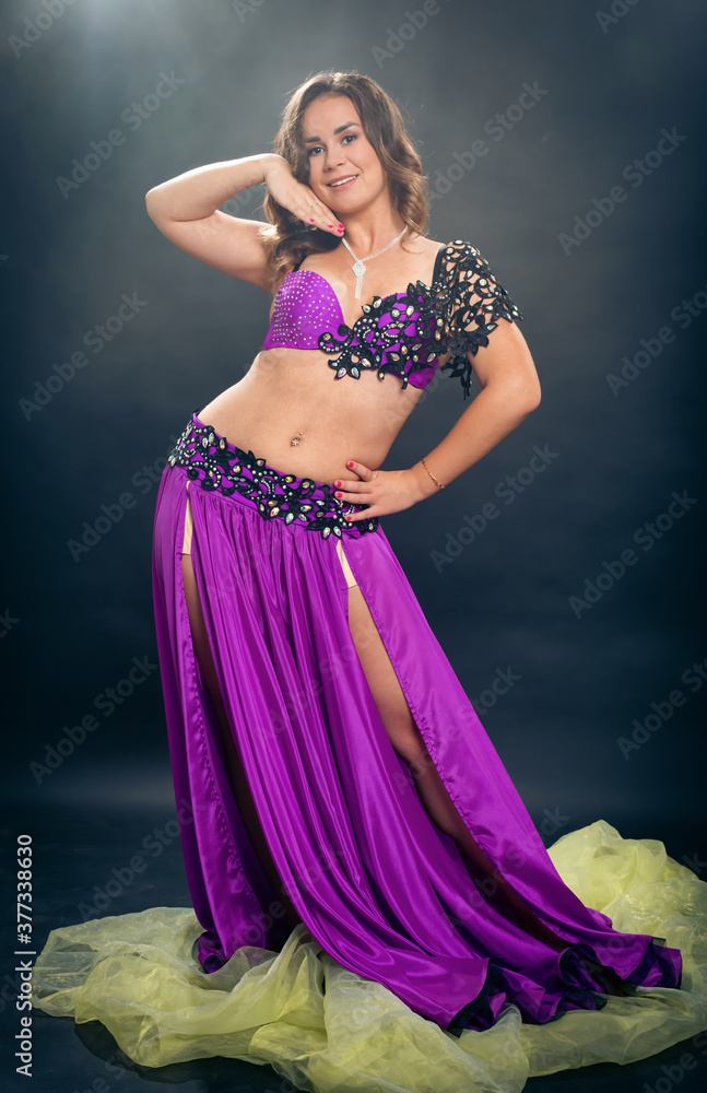 Obraz premium A belly dance soloist poses in a purple concert costume
