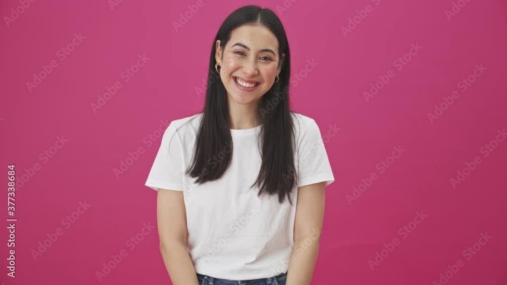 A cheerful smiling woman is standing isolated over a pink background A cheerful smiling woman is standing isolated over a pink background