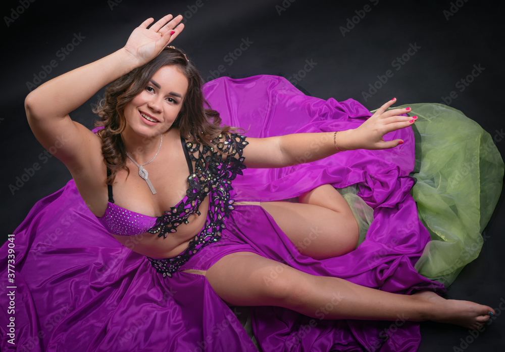 Obraz premium A belly dance soloist poses in a purple concert costume