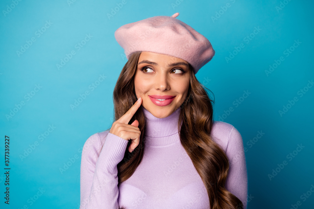 Closeup photo of minded charming lady beaming smiling look side empty space hand on cheek wear pink cap beret purple turtleneck jumper isolated blue color background Closeup photo of minded charming lady beaming smiling look side empty space hand on cheek wear pink cap beret purple turtleneck jumper isolated blue color background