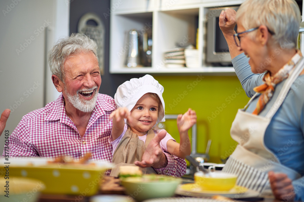 grandparents having fun with their granddaughter in the kitchen