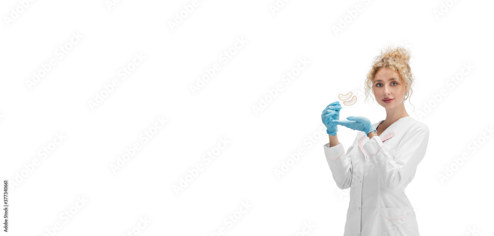 Eye patches. Portrait of female doctor, nurse or cosmetologist in white uniform and blue gloves over white studio background. Copyspace for ad. Concept of healthcare and medicine, beauty. Flyer Eye patches. Portrait of female doctor, nurse or cosmetologist in white uniform and blue gloves over white studio background. Copyspace for ad. Concept of healthcare and medicine, beauty. Flyer