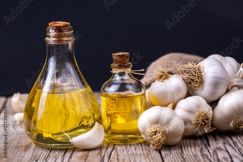 Glass bottle of garlic oil and Ripe and fresh garlic plant on wooden or rustic table, alternative medicine, organic cleaner.