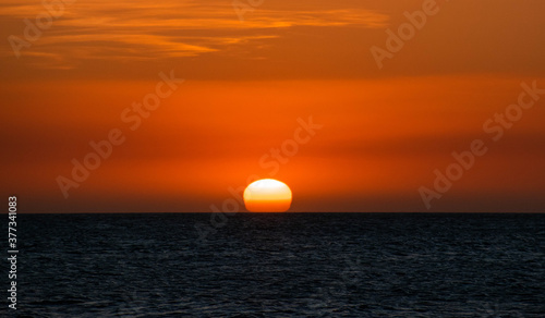 Fototapeta Naklejka Na Ścianę i Meble -  Sun hiding by the ocean