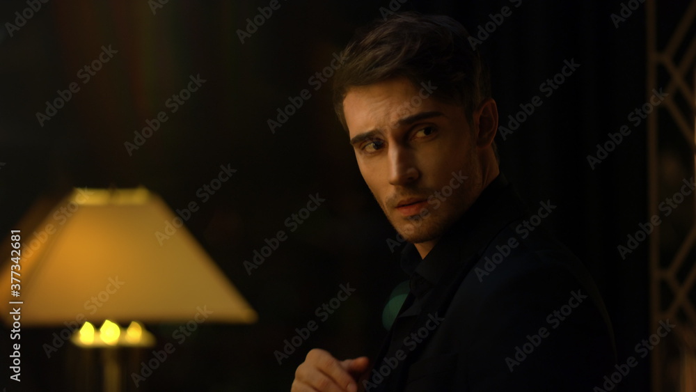 Top manager straightening shirt in dark room. Attractive man looking around. Top manager straightening shirt in dark room. Attractive man looking around.