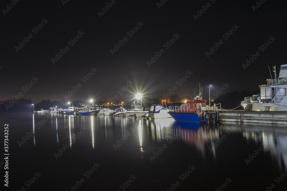 Night landscape with a view of the Parking lot of ships and boats. Floodlights illuminate the boat station.