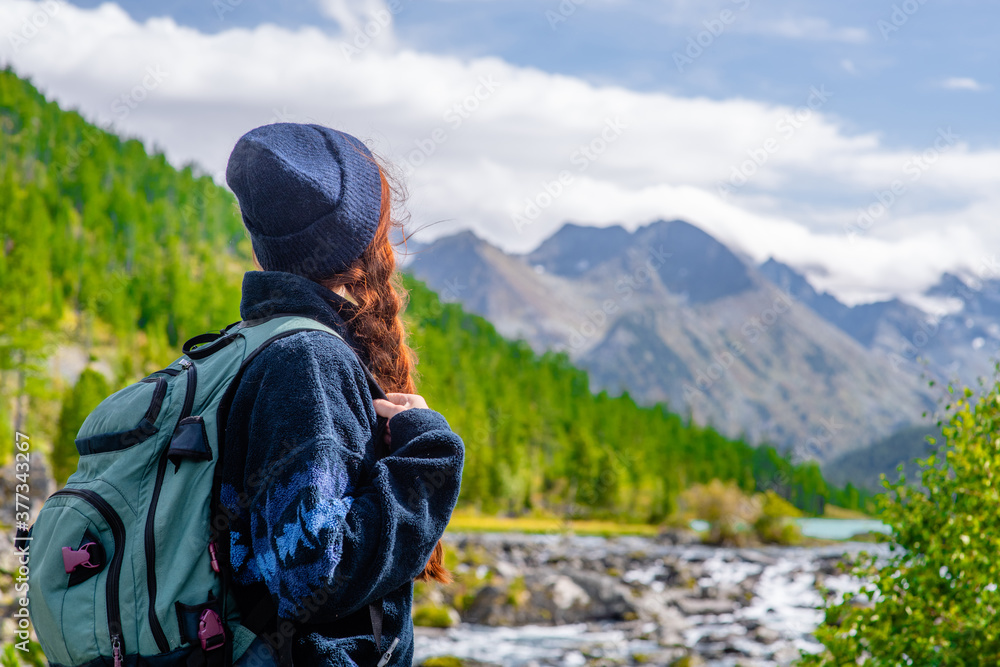 Young woman with backpack enjoys the view of enjoys the view of the Multinsky lake. Empty space for text