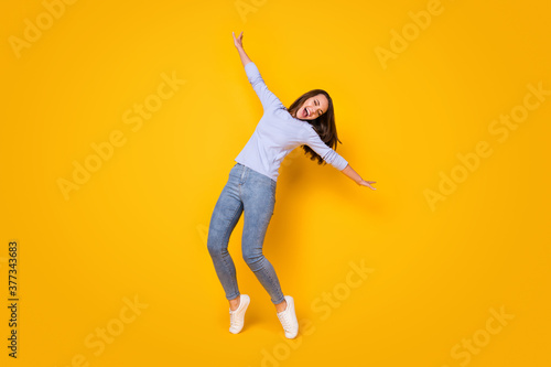 Full length body size view of her she attractive pretty overjoyed dreamy cheerful cheery girl jumping having fun dancing singing chill isolated bright vivid shine vibrant yellow color background