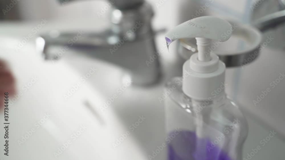 Young Man Using Soap Dispenser, then Washing Hands in background Young Man Using Soap Dispenser, then Washing Hands in background