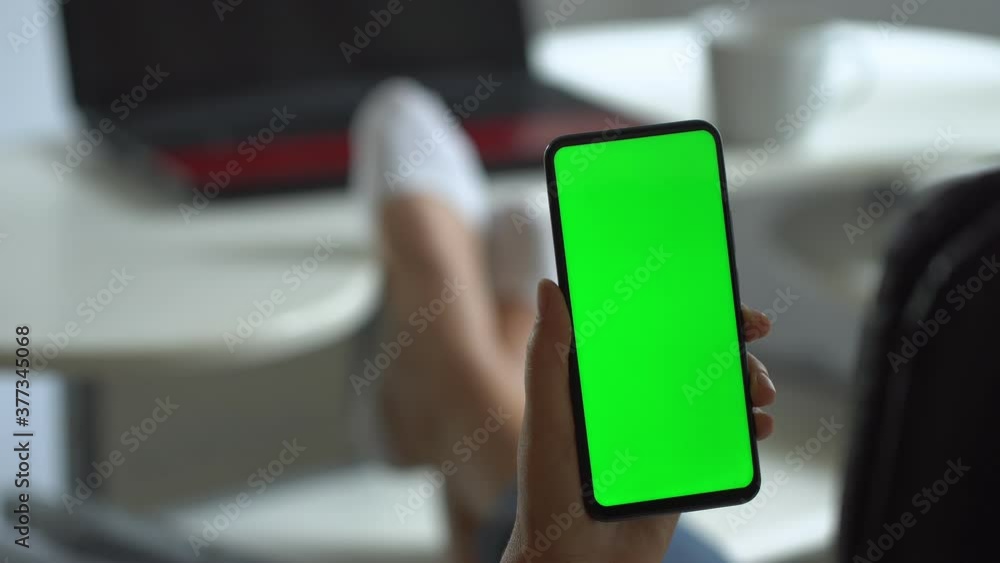 Handheld Camera: Point of View of Woman at Modern Room Sitting on a Chair Using Phone With Green Mock-up Screen Chroma Key Surfing Internet Watching Content Videos Blogs