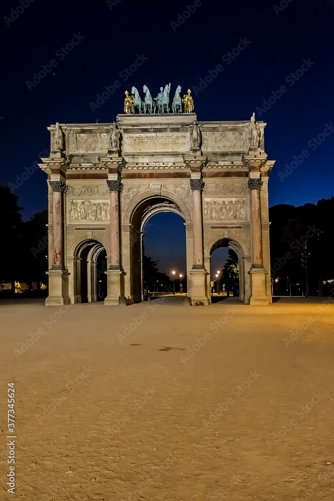 Triumphal Arch (Arc de Triomphe du Carrousel) at night in Tuileries gardens in Paris. Monument built between 1806 - 1808 to commemorate Napoleon's military victories. Paris, France.
