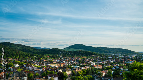 Germany, Freiburg im Breisgau, Houses, Churches and skyline between green mountains and trees, aerial view above the city © Simon
