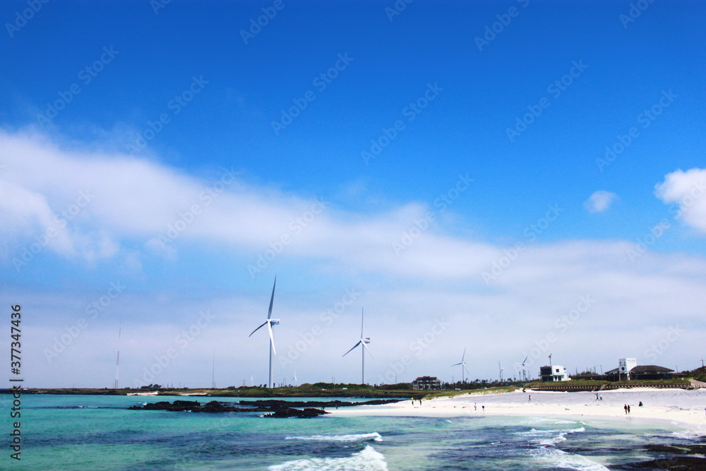 Blue sky, beach, ocean and wind turbines in Jeju Island, Korea