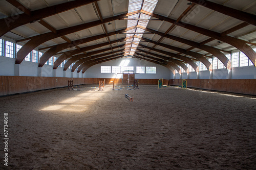 A light-flooded riding arena with some jumping obstacles.