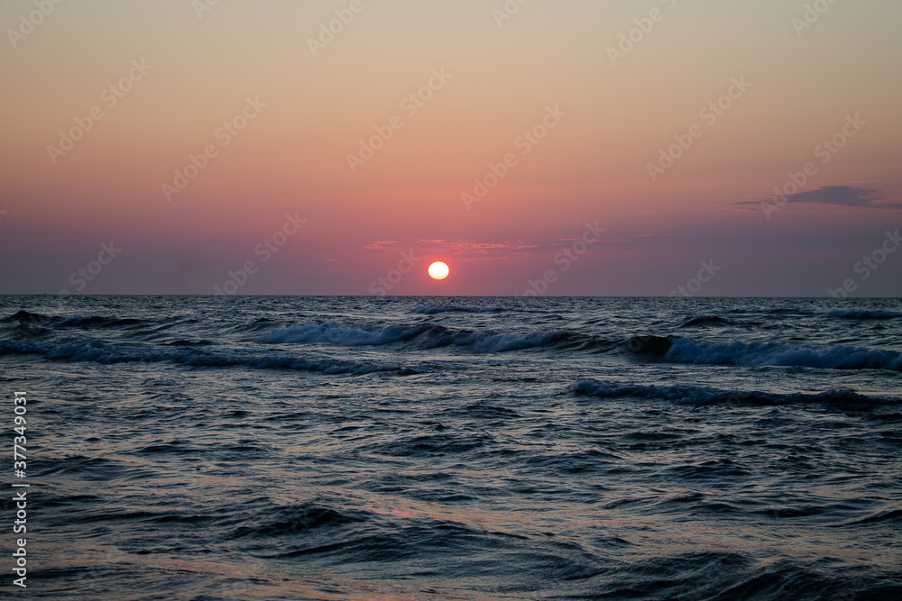 Romantic sunset by the sea. The setting sun over the waves.