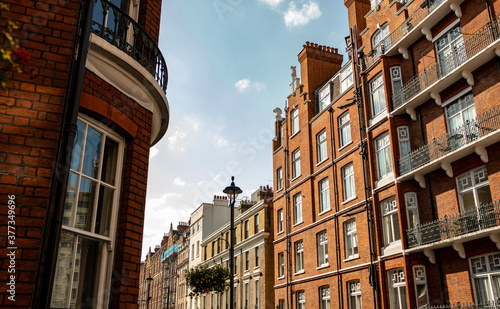 Looking up at red brick London townhouses against blue sky © William