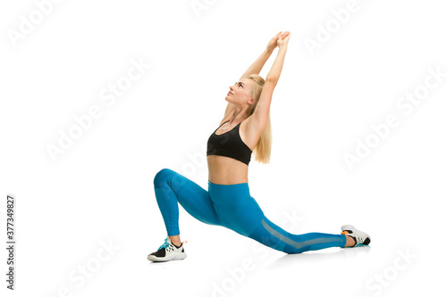 Stretching. Beautiful female fitness coach practicing isolated on white studio background, showing exercises. Caucasian blonde model in sport outfit. Professional occupation, active and healthy