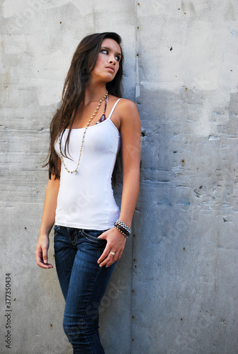 Sexy beautiful female brunette long hair jeans urban concrete