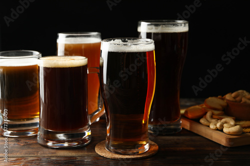 Glasses of beer and snacks on wooden table