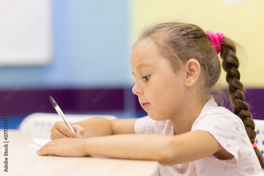 Young girl taking notes in class at school bending over his paperwork Young girl taking notes in class at school bending over his paperwork