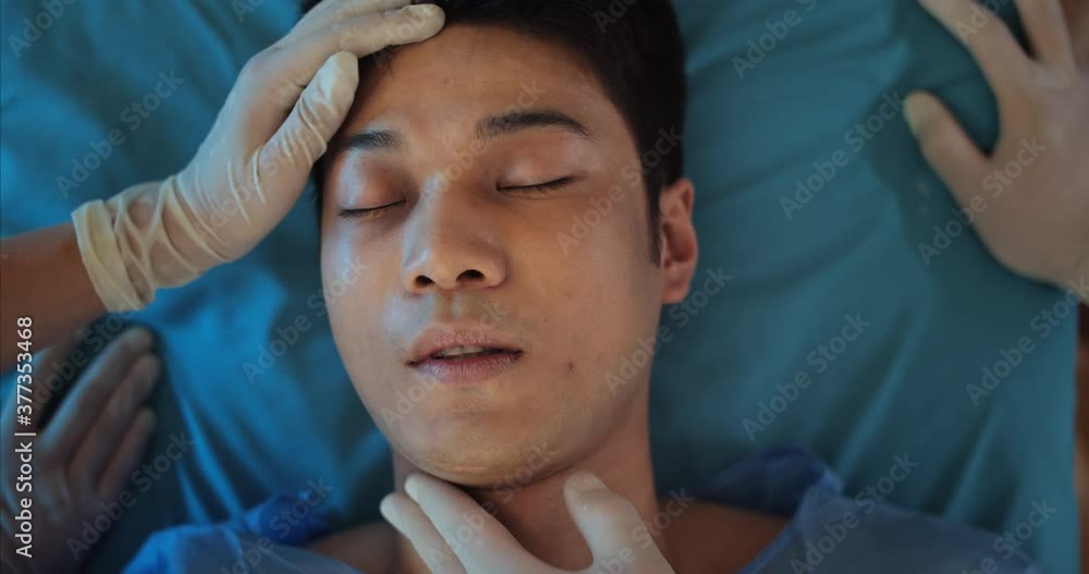Top view of young guy lying on medical transportation stretcher while paramedic checking pulse. Close up of ill millennial man looking to camera while riding in ambulance to hospital Top view of young guy lying on medical transportation stretcher while paramedic checking pulse. Close up of ill millennial man looking to camera while riding in ambulance to hospital