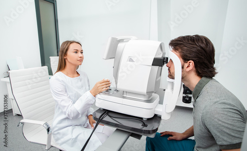Optometrist using autorefractor check patient vision. Eye exam of adult people photo