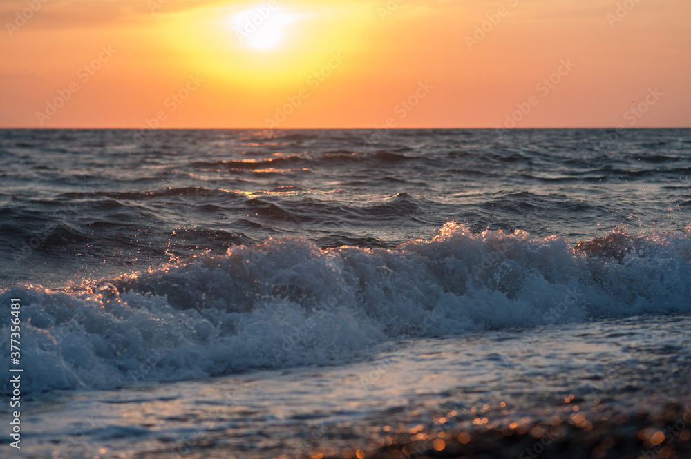 Sunset at sea, waves in the rays of sunset