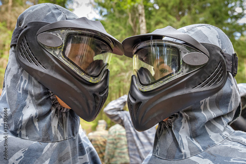 Cool man and woman in paintball masks look at each other