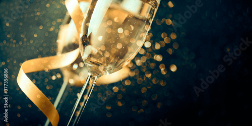 Sticker Two champagne glasses with golden ribbon and gold glitter splash bokeh on dark background