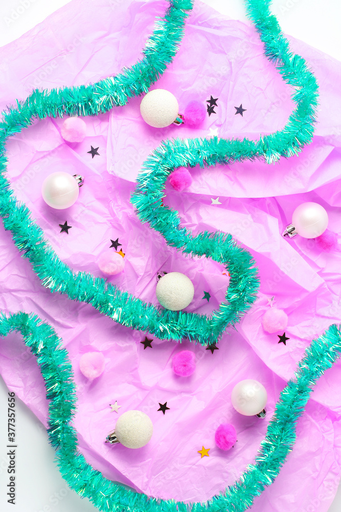 holiday concept. composition of brightly turquoise tinsel, balls, pomopons and confetti on a pink background. flat lay, top view.