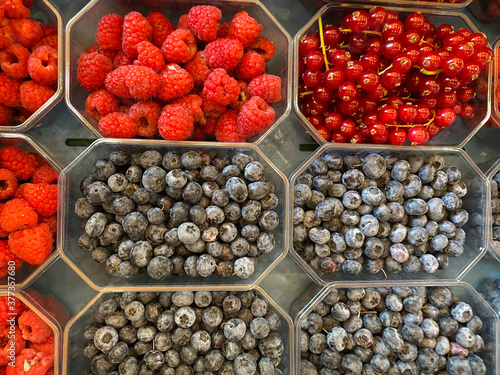 High angle view on different fresh ripe berries in plastic bowls on german farmer market
