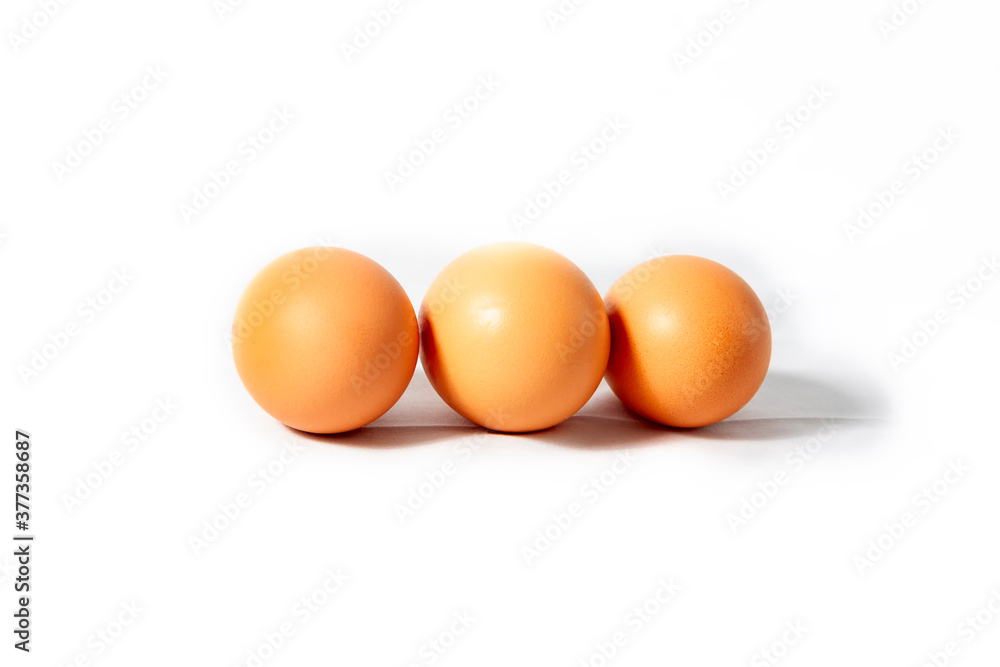 Three brown eggs on a white background. Three brown eggs on a white background.